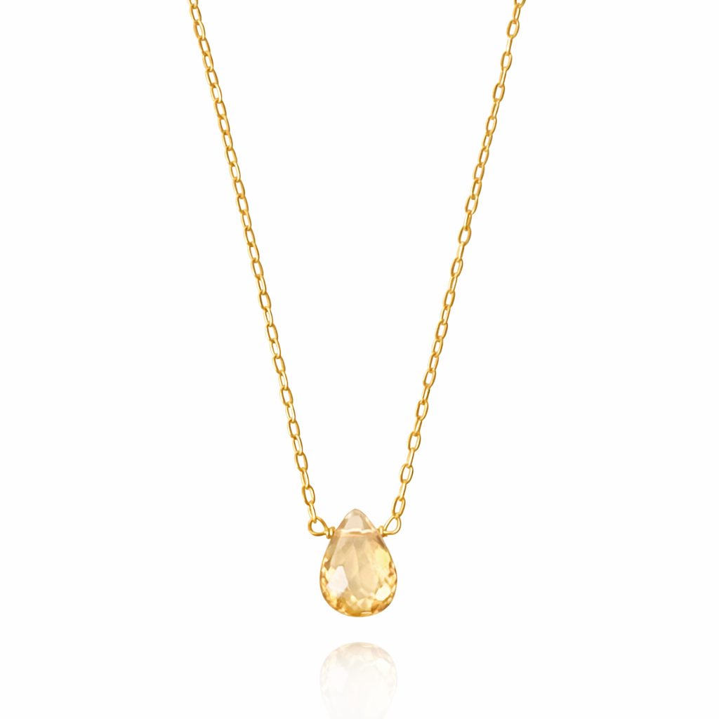 Gold necklace with a teardrop-shaped yellow gemstone on a white background